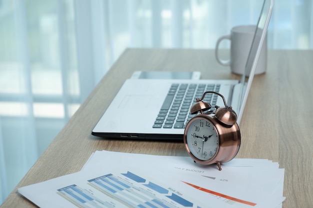 White laptop and alarm clock on the desk