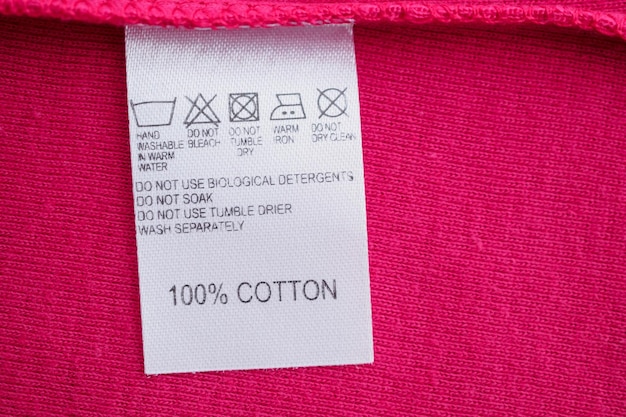 White laundry care washing instructions clothes label on red cotton shirt