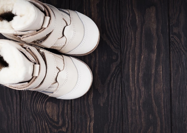 White leather children's shoes on a wooden background, a copy of the space.