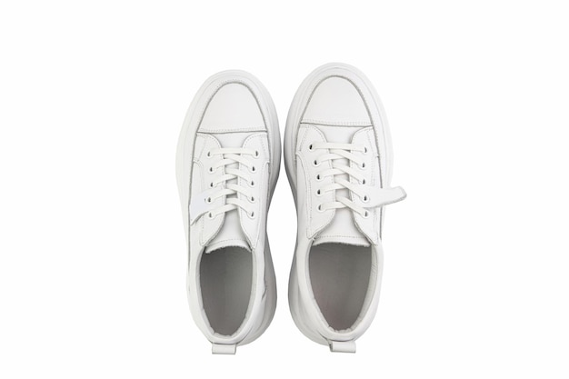 White leather sneakers Casual women's style White lacing and white rubber soles Isolated closeup on white background Top view Fashion shoes