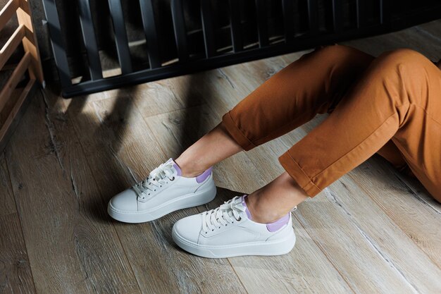 White leather sneakers on womens legs Womens legs in comfortable casual sneakers