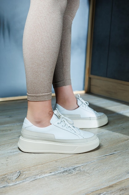 White leather womens classic sneakers on the feet Stylish womens shoes for the summer Collection of summer womens shoes