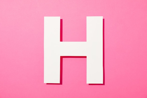 White letter H on pink background