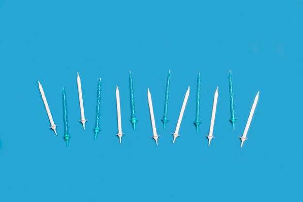 White and light blue birthday candles on a blue background with copy space