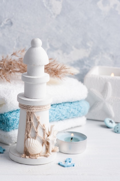 White lighthouse in scandinavian interior with towels and dry flowers and lit candle