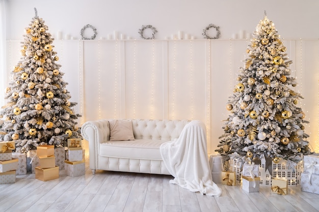 White living room interior with new year trees decorated gift boxes and modern sofa golden color