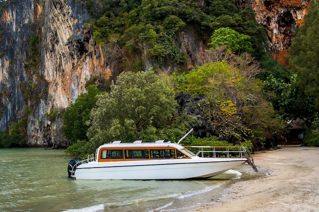 White luxury motor speedboat waiting passenger on the shore of a tropical island Moored on sand