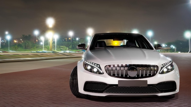 A White Luxury Sedan Car in blue lagoon at night. Front view