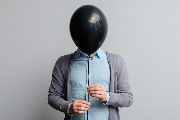 A white man covers his face with a black balloon Hiding from pr