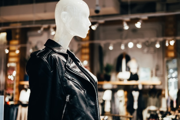 White mannequin in black leather jacket in fashion store, selective focus.