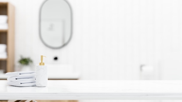 White marble tabletop with towels shampoo bottle and empty mockup space over blurred bathroom