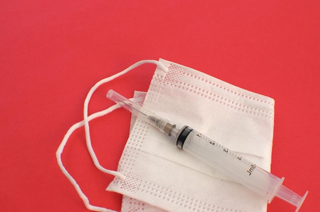 White mask on the side on a red surface protective mask used in medicine worldwide Vaccination preve