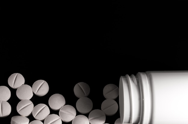 Photo white medical pills and tablets on black background closeup photo of medical preparations with copy space