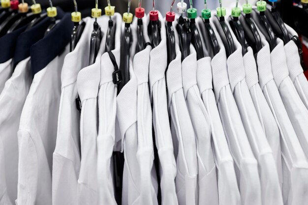 Photo white men's shirts on a hanger in a clothing store. white men's shirts hang on the shoulders.