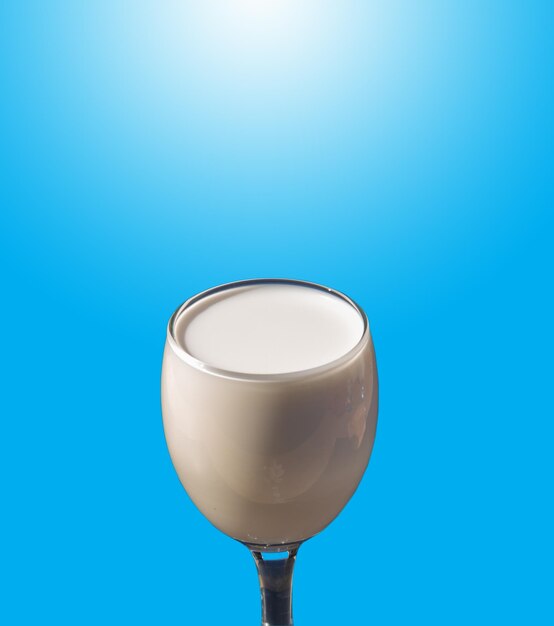 White milk in clear glass. Blue background and white sunlight on the above(perspective view).