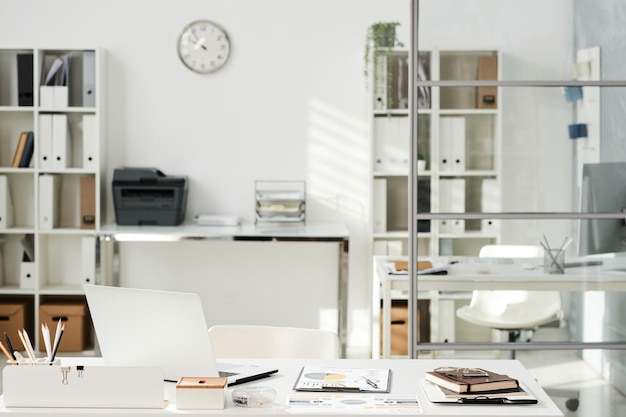 White minimalistic office interior furnished with shelves with documents tables and chairs