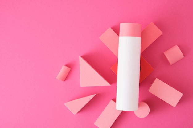 White mock up bottle with shampoo or shower gel and geometric shapes forms. Exhibition podium, platform for product presentation on pink background. top view