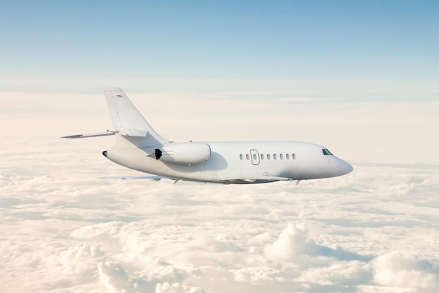 White modern luxury business jet flies in the air above the clouds