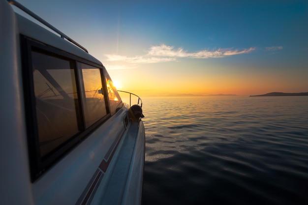 White motorboat moving to sunset