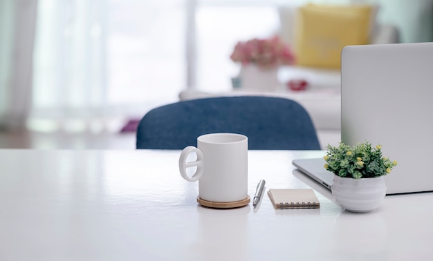 White mug and laptop on white wooden table