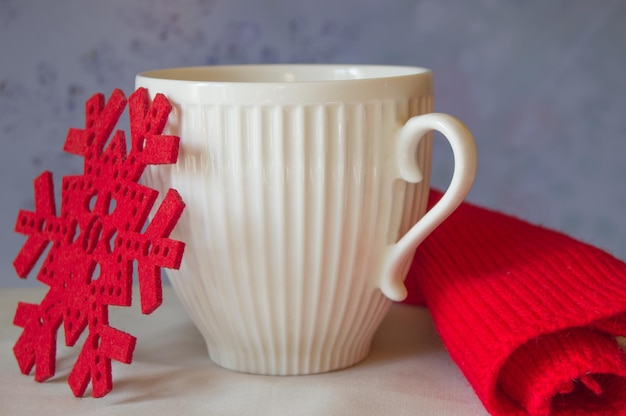 White mug and snowflake with a red knitted scarf The Concept Of Christmas