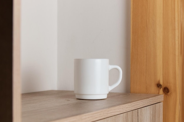 White mug for tea and coffee in on a wooden table closeup