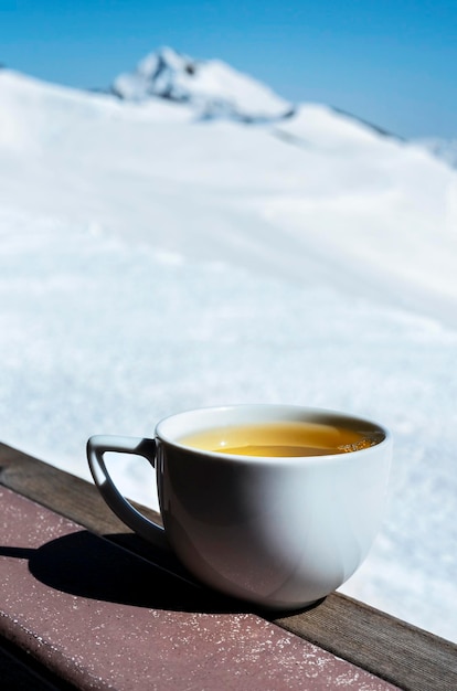 White mug with hot tea on background of snowy mountain range  Relaxation in nature Landscape