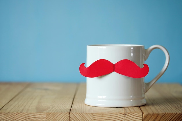 A white mug with a red paper mustache congratulations or a gift to dad