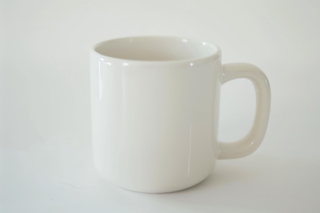 Photo a white mug with a simple round handle sits on a white background ready for a new design or a steaming beverage