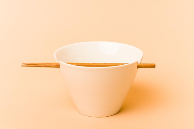 White noddles bowl with chopstick isolated on beige background