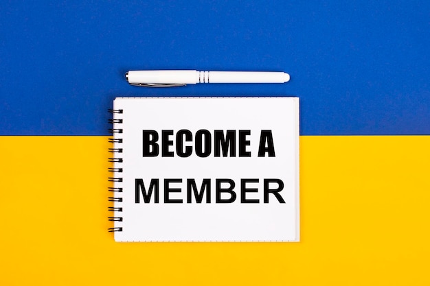 A white notebook with the text BECOME A MEMBER and a white pen on a blue and yellow background