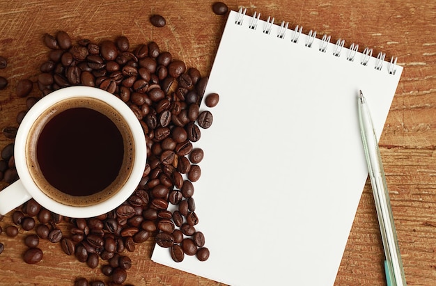 White notebook for writing and coffee on wooden table