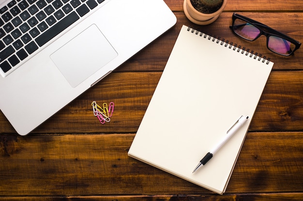 White notebooks and laptop laying on a wooden table 