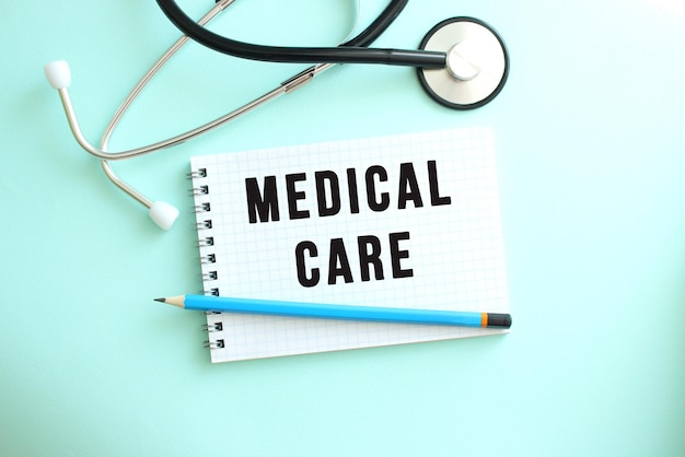 White notepad with the words MEDICAL CARE and a stethoscope on a blue background