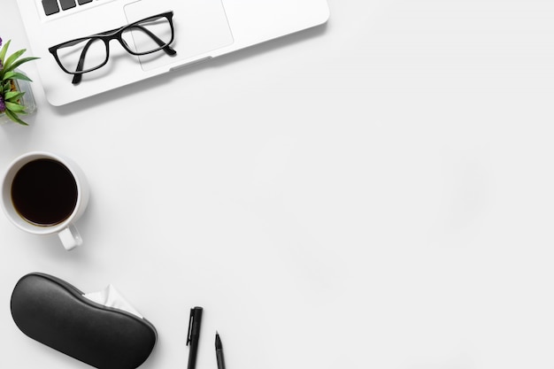 White office desk table with laptop, cup of coffee and supplies.