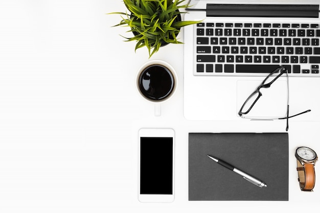 White office desk table with laptop, smartphone and office supplies.