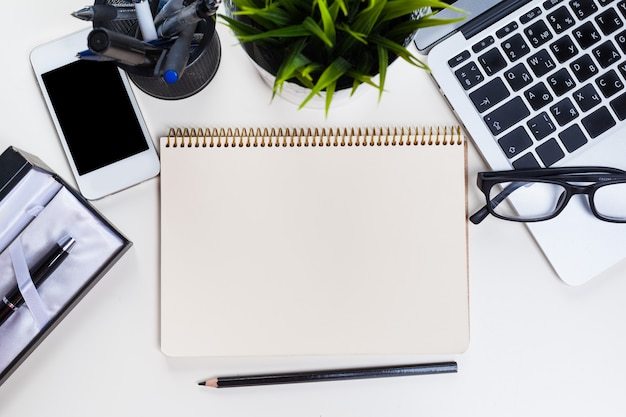 White office desk table with a lot of things on it. 