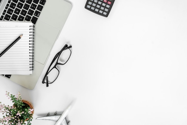 White office desk with blank notebook, tablet, calculator, computer and other office supplies