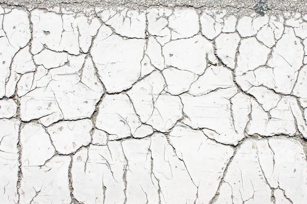 White old cracked paint cracked by the heat in the sun on the concrete surface Great for design and texture background