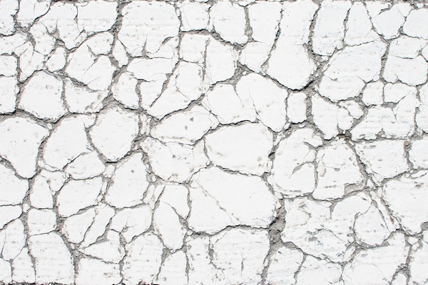 White old cracked paint cracked by the heat in the sun on the concrete surface Great for design and texture background