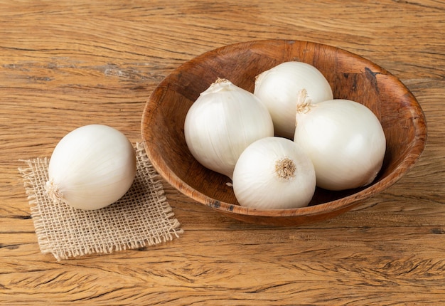 White onions in a bowl over wooden table.