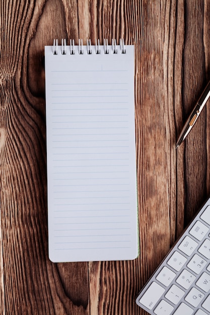 The white open notepad and computer keypad isolated on the wooden desktop