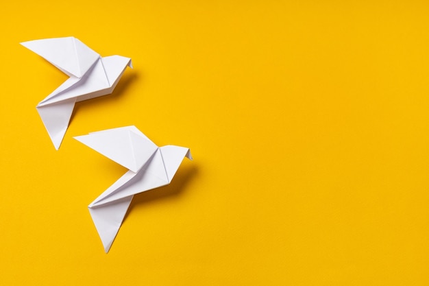 White origami doves as a symbol of faith hope and peace on a yellow background