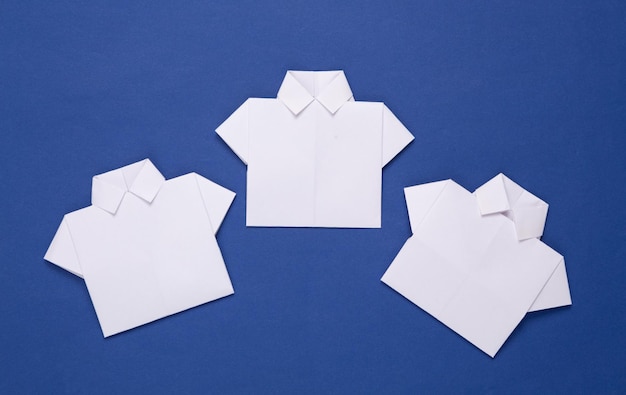 White origami paper shirts on blue background