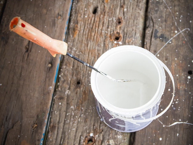 White paint bucket  and roller on wood background