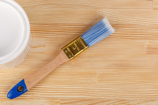 White paint with a brush on a wooden background with texture