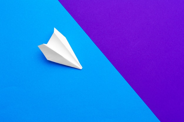 White paper airplane on a color block blue and purple 