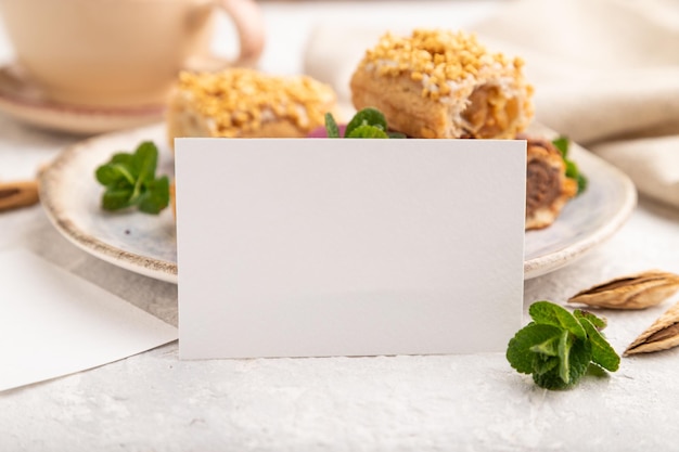 White paper business card and set of eclair on gray concrete background side view side view close up