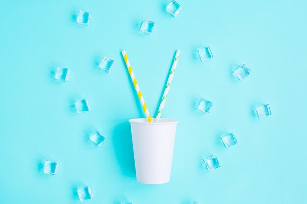 Photo white paper caps with color cocktail straw on blue background.