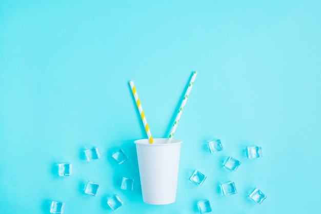 White paper caps with color cocktail straw on blue background.